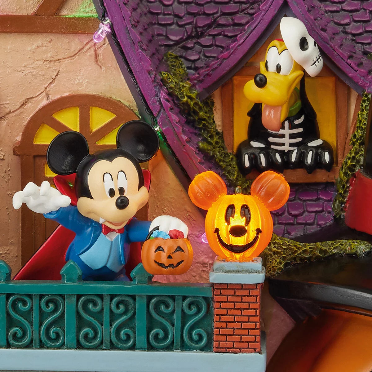 Hand-crafted Disney animated Halloween house centerpiece displaying illuminated LED lights, classic characters around a giant Jack-o-Lantern, set indoors on a wooden mantle.