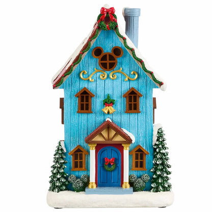 Complete 13-piece lighted Disney Christmas village featuring hand-painted Mickey Mouse figures, glowing LED snow-covered houses, and illuminated archway on a wooden table.