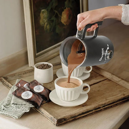 Front view of the grey Dualit Milk Frother Max displaying the froth adjustment dial, non-drip spout, and cool-touch body on a modern kitchen countertop.