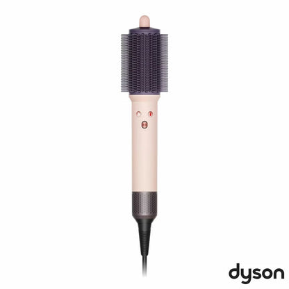 Dyson Airsmooth styling brush in Ceramic Pink with teardrop brush head and soft dual bristles sitting on a vanity table.
