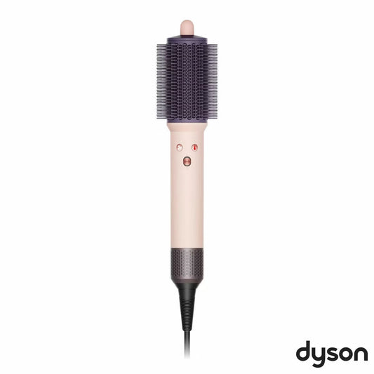 Dyson Airsmooth styling brush in Ceramic Pink with teardrop brush head and soft dual bristles sitting on a vanity table.