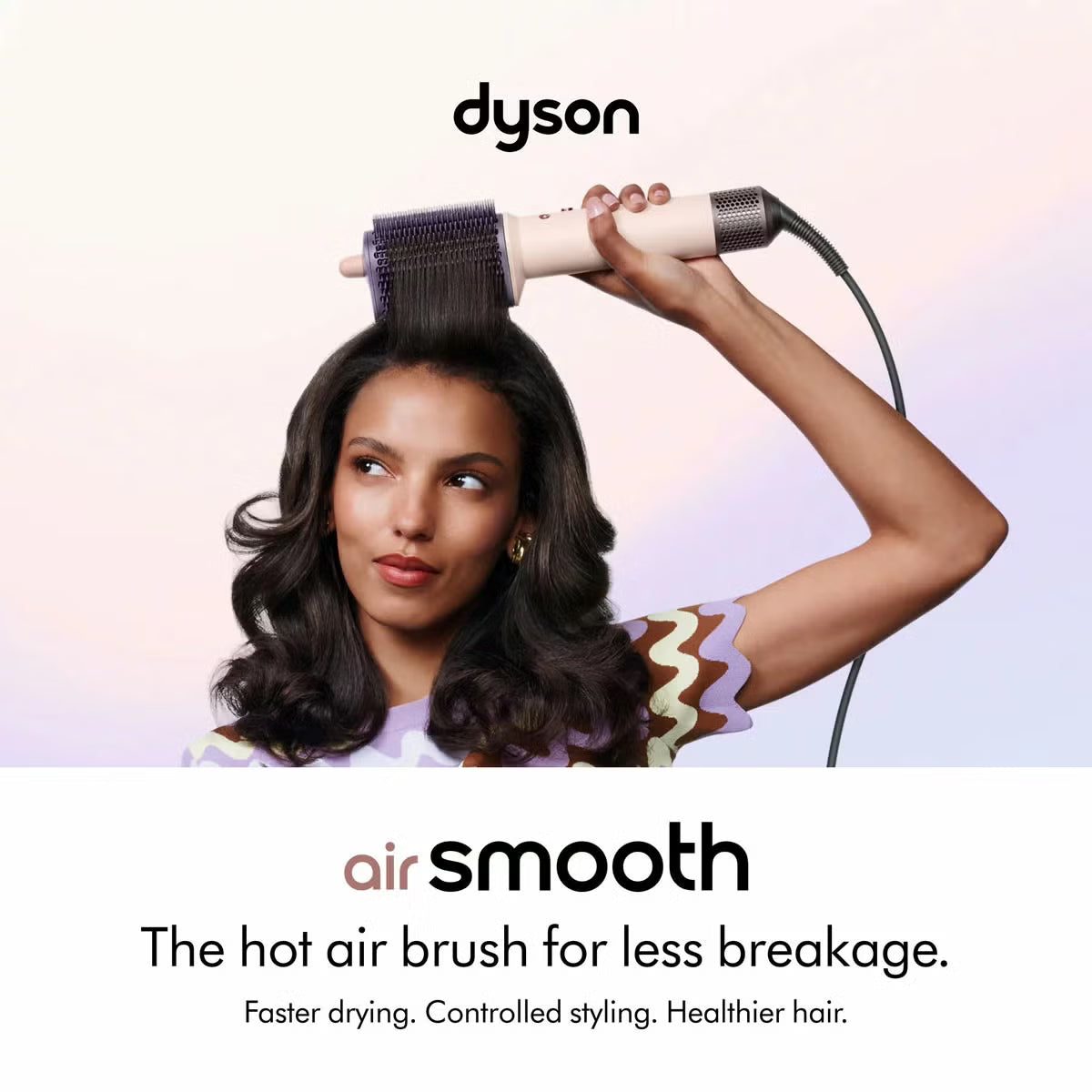 Dyson Airsmooth styling brush in Ceramic Pink with teardrop brush head and soft dual bristles sitting on a vanity table.