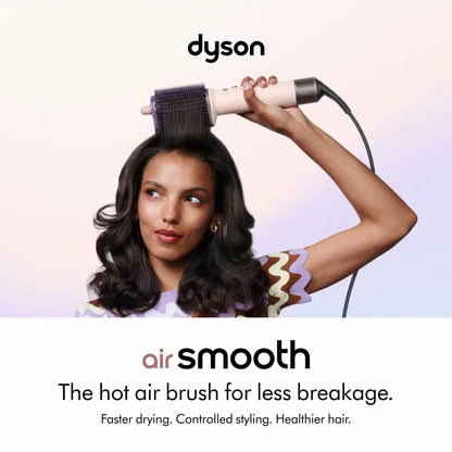 Dyson Airsmooth styling brush in Ceramic Pink with teardrop brush head and soft dual bristles sitting on a vanity table.