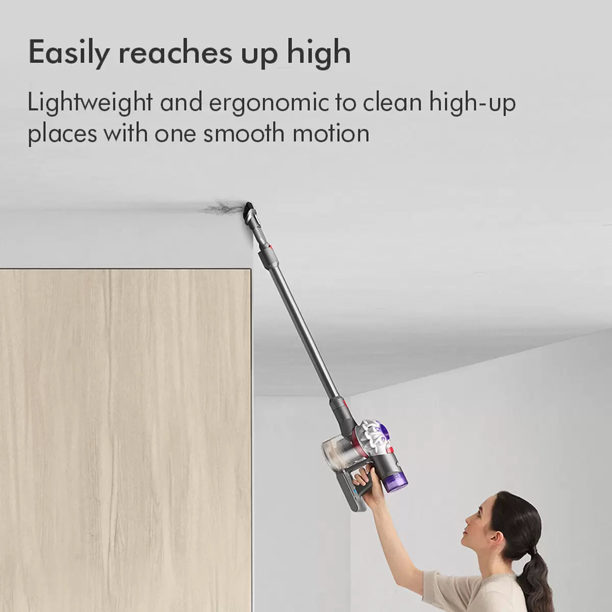 Side profile of the nickel and iron Dyson V8 Advanced cordless stick vacuum cleaner mounted upright on a neutral modern wall dock.