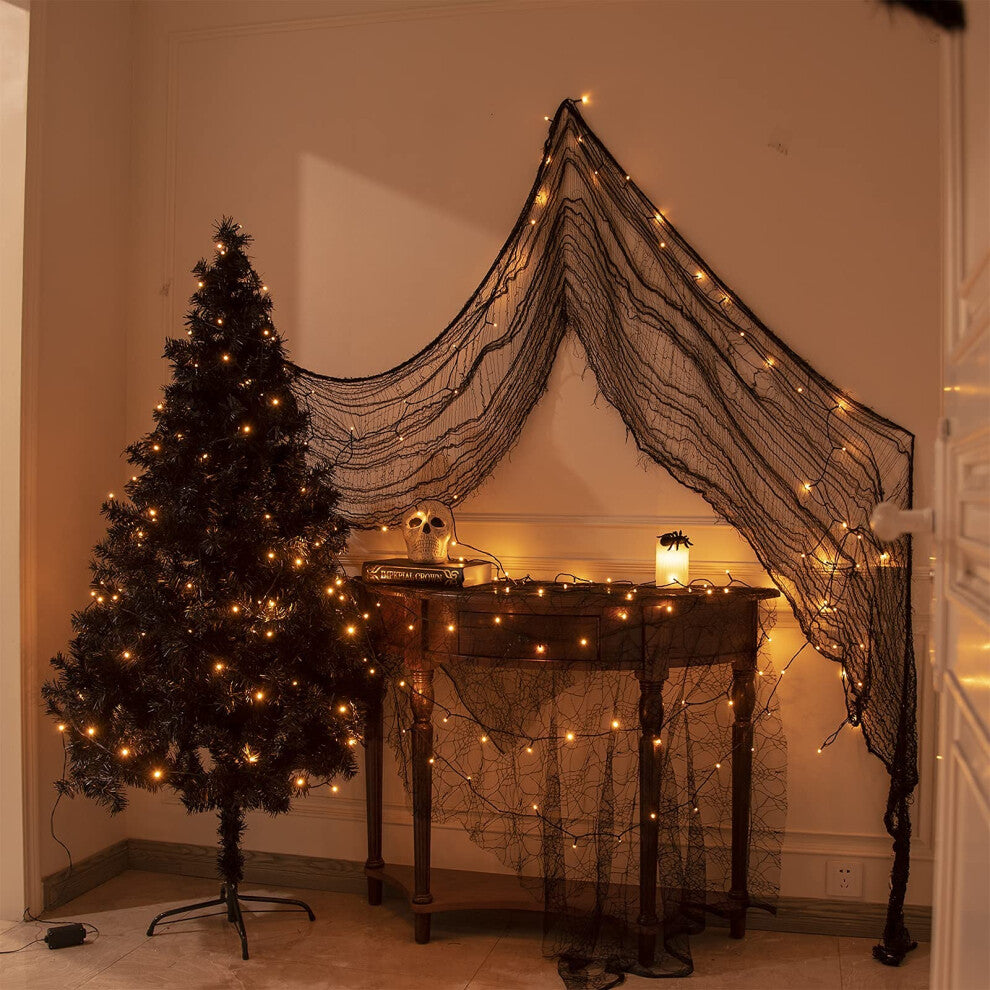 A 20m string of 200 orange LED fairy lights on a black cable glowing across an outdoor haunted house display at night.
