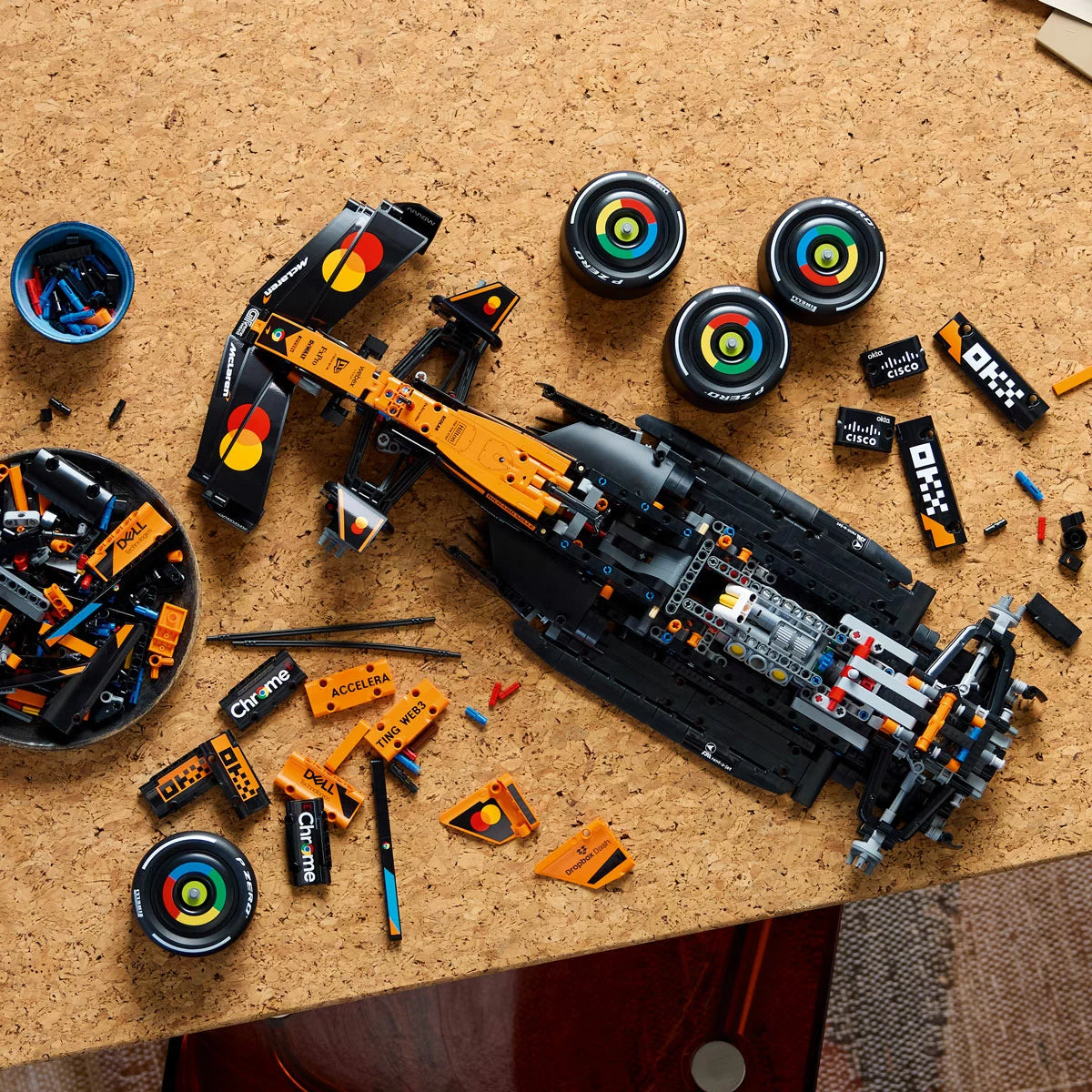 Three-quarter overhead shot of the massive built papaya orange and black LEGO 42228 McLaren Formula 1 racing car model displayed on a gray surface.