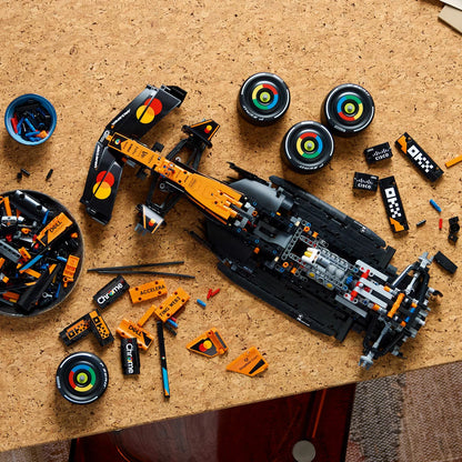 Three-quarter overhead shot of the massive built papaya orange and black LEGO 42228 McLaren Formula 1 racing car model displayed on a gray surface.