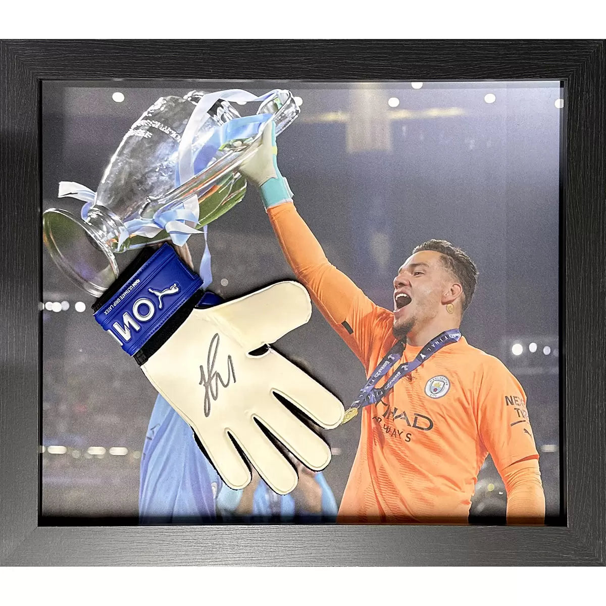 A professionally framed Puma goalkeeper glove signed by Ederson, presented in a sleek black frame with a certificate of authenticity visible.