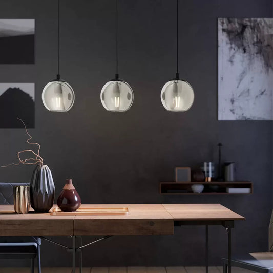 Eglo Ariscani 3-light ceiling pendant featuring three smoked glass ball shades suspended from a black steel bar over a kitchen island.