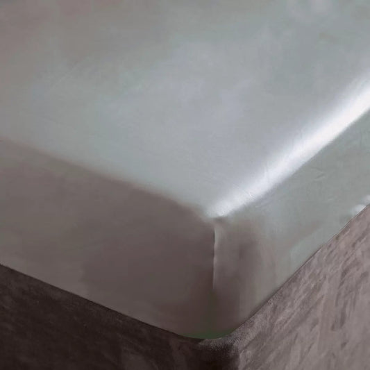A close-up studio photograph showing the platinum silver-grey Belledorm 1000 thread count sateen fitted sheet pulled smoothly and tightly over the corner of a contemporary mattress.