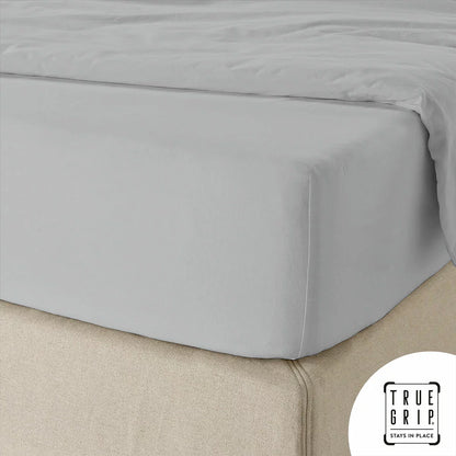 A close-up overhead shot of a neatly tucked Purity Home charcoal grey 400 thread count cotton fitted sheet stretched tightly over a deep mattress corner.