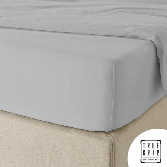 A close-up overhead shot of a neatly tucked Purity Home charcoal grey 400 thread count cotton fitted sheet stretched tightly over a deep mattress corner.