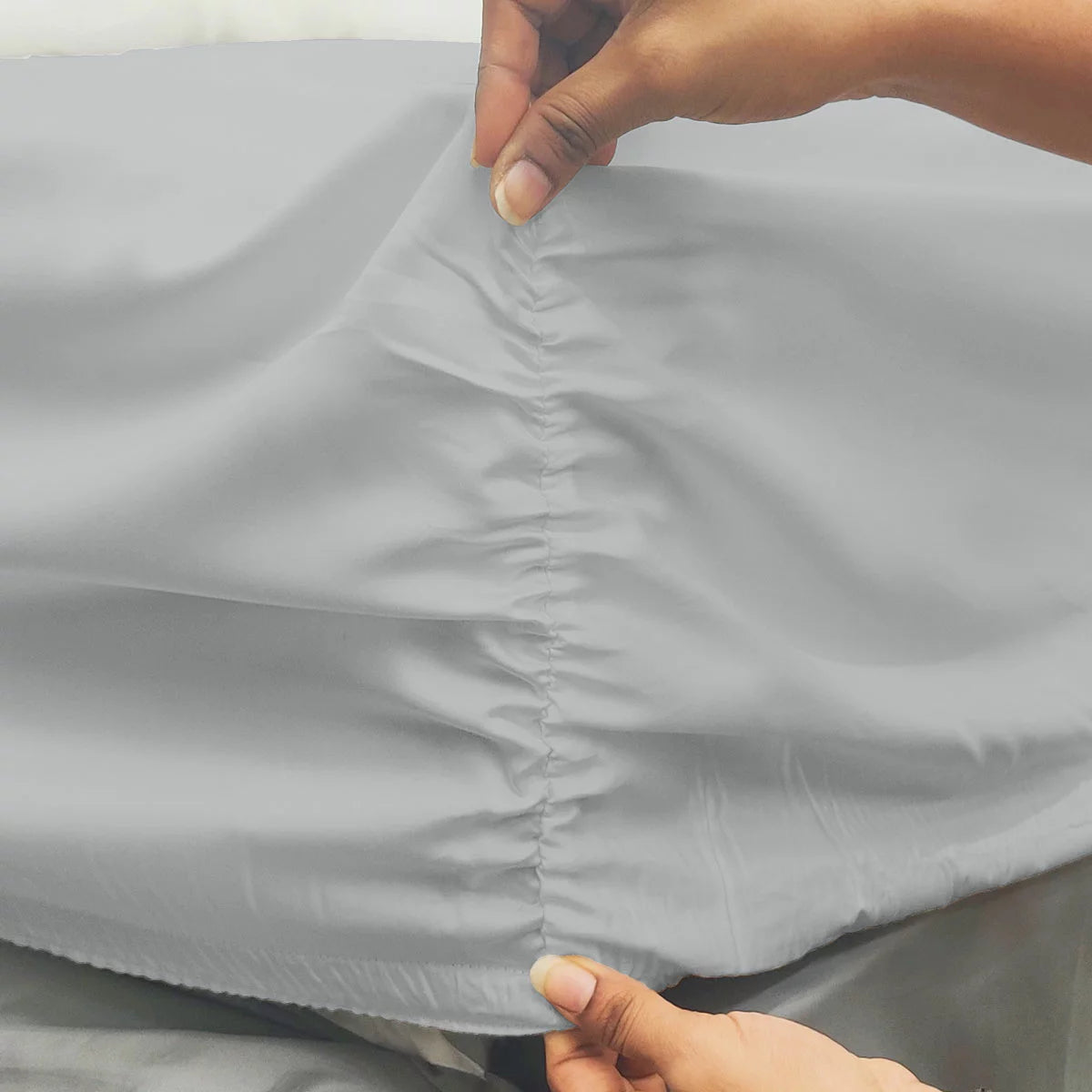 A close-up overhead shot of a neatly tucked Purity Home charcoal grey 400 thread count cotton fitted sheet stretched tightly over a deep mattress corner.