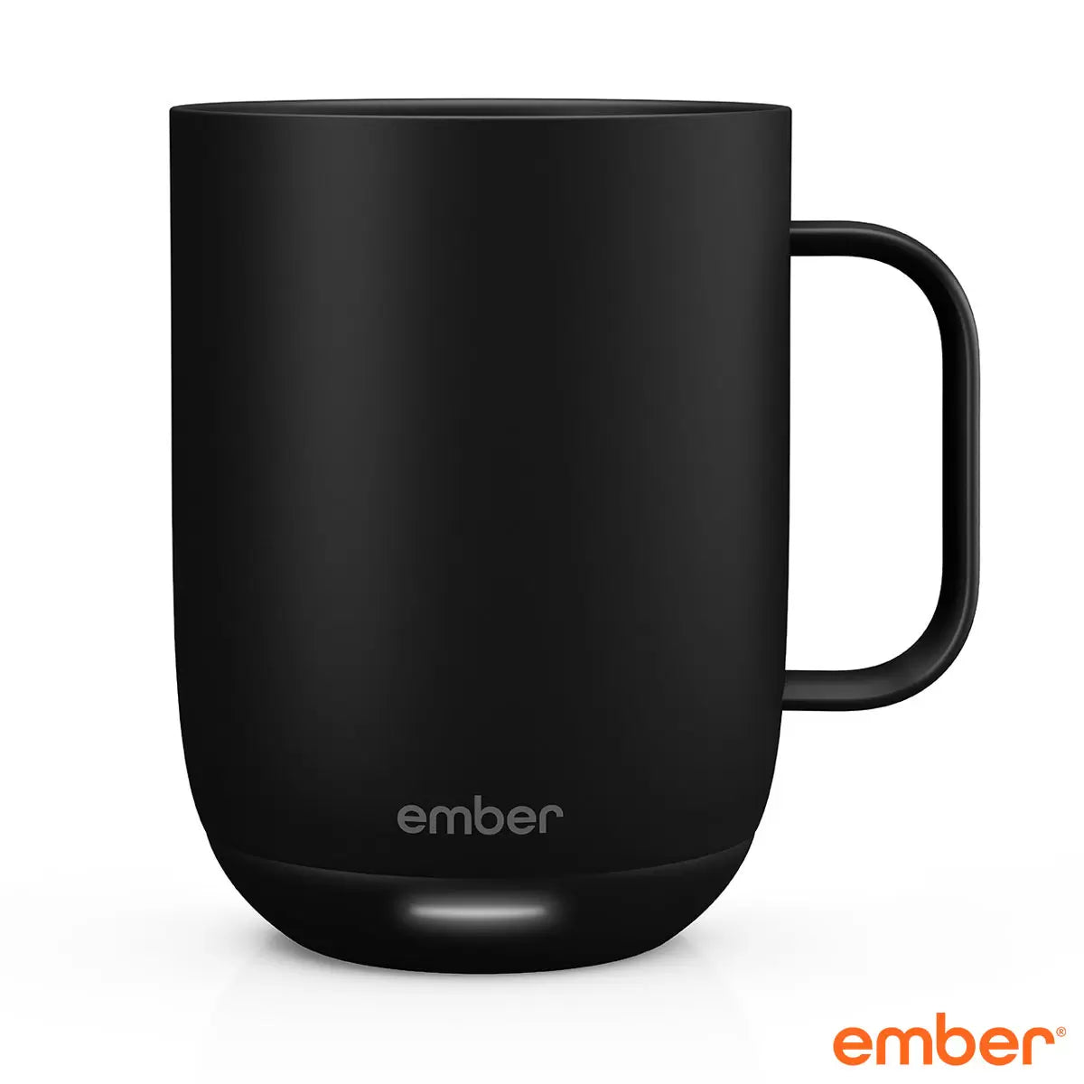 Matte black Ember Mug 2 ceramic smart mug sitting on its charging coaster next to a laptop on a modern wooden desk setting.