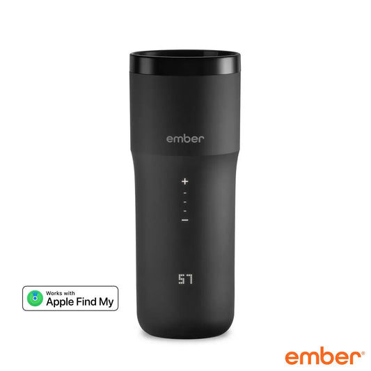 Matte black Ember Temperature Control Travel Mug 2+ with illuminated digital touch display resting on its charging coaster on a wooden office desk.