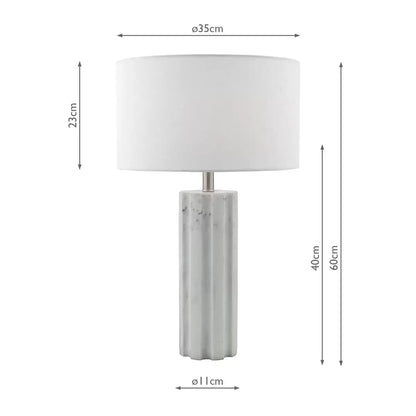 Front view of the Erebus table lamp showcasing its cylinder-shaped matte white marble effect resin base, polished chrome metal collar, and white linen drum shade on a glass desk.