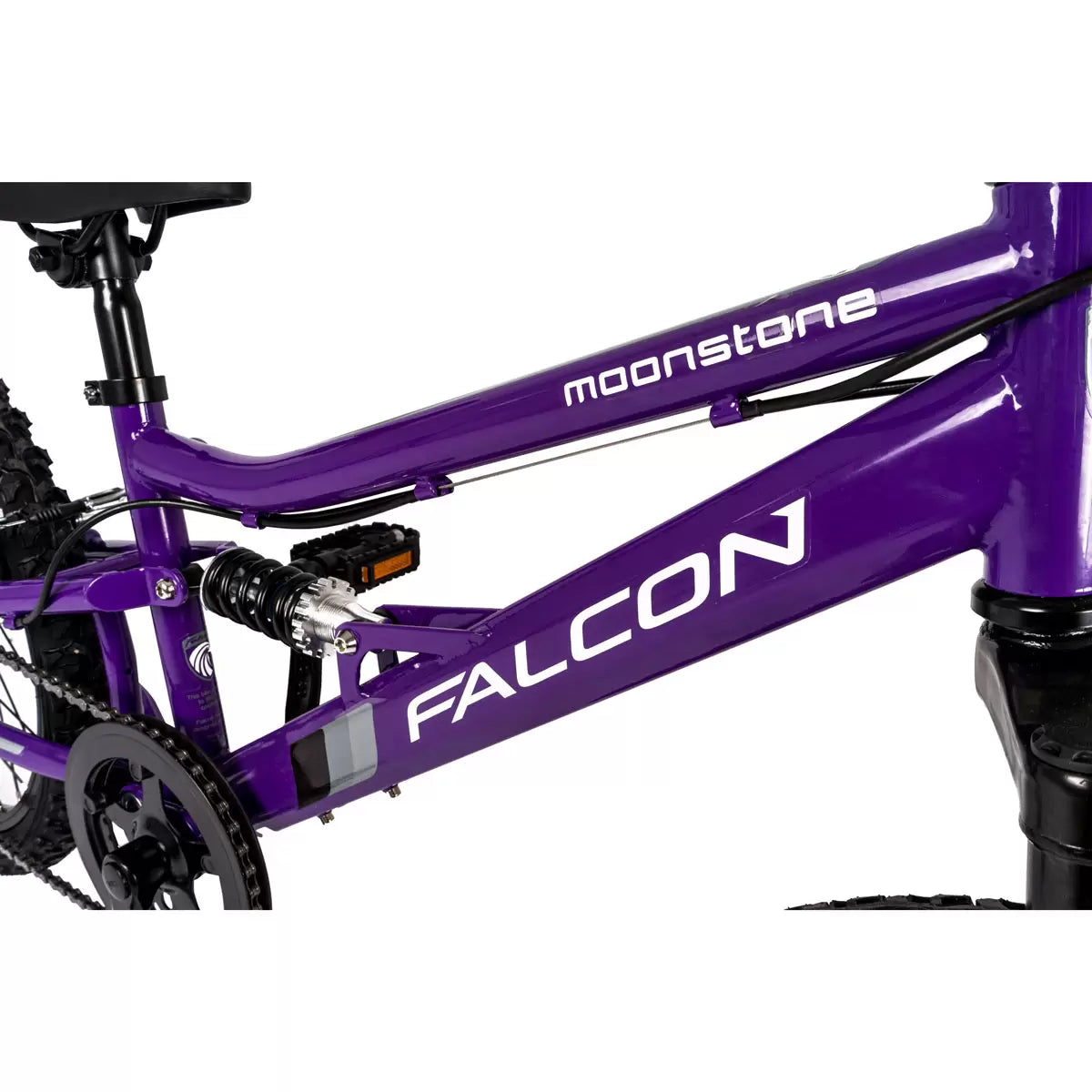 A vibrant purple Falcon Moonstone junior dual-suspension mountain bike with 20-inch knobbly black tyres, a rear spring shock absorber, and prominent white decals, parked on a gravel trail.