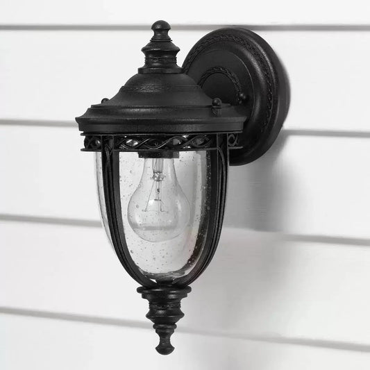 A compact Feiss English Bridle 1-light exterior wall lantern featuring a bronze finish and seeded glass panels on a cottage wall.