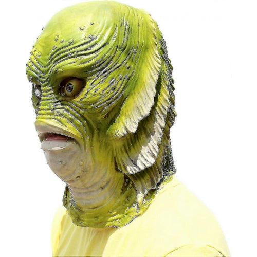Front view of a detailed latex green fish monster mask with bulging eyes and open mouth resting on a tabletop setting.