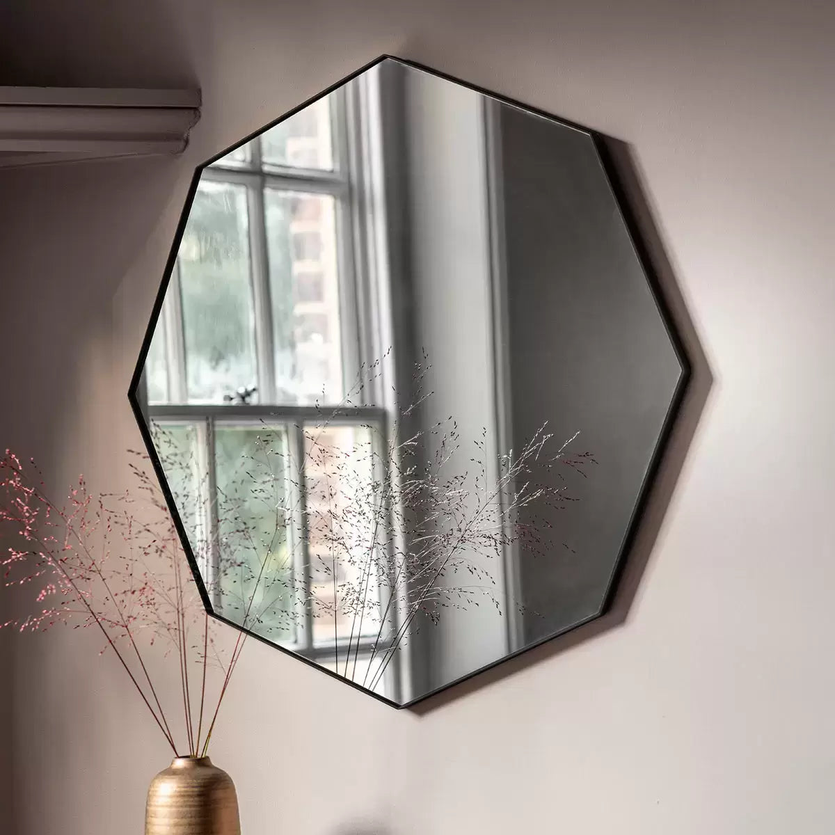 Front view of the 80cm Gallery Bowie octagonal wall mirror featuring a sleek black metal frame mounted on a neutral living room wall.