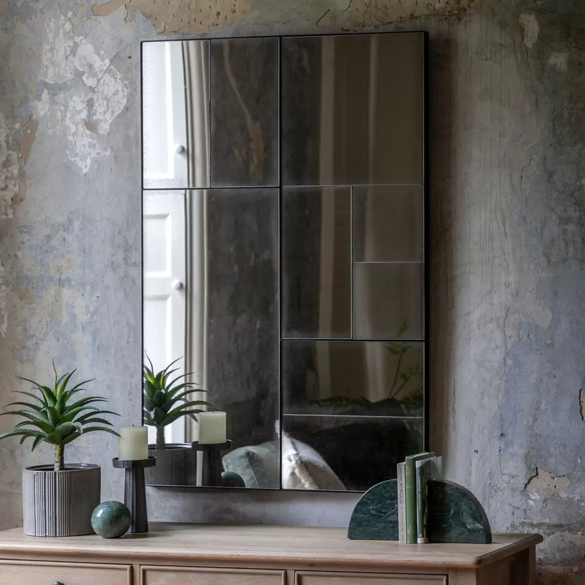 Front view of the Gallery Broadheath rectangular mirror featuring an antique distressed glass panel grid set in a black metal frame hung vertically on a neutral living room wall.