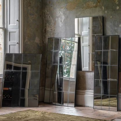 Front view of the Gallery Broadheath rectangular mirror featuring an antique distressed glass panel grid set in a black metal frame hung vertically on a neutral living room wall.