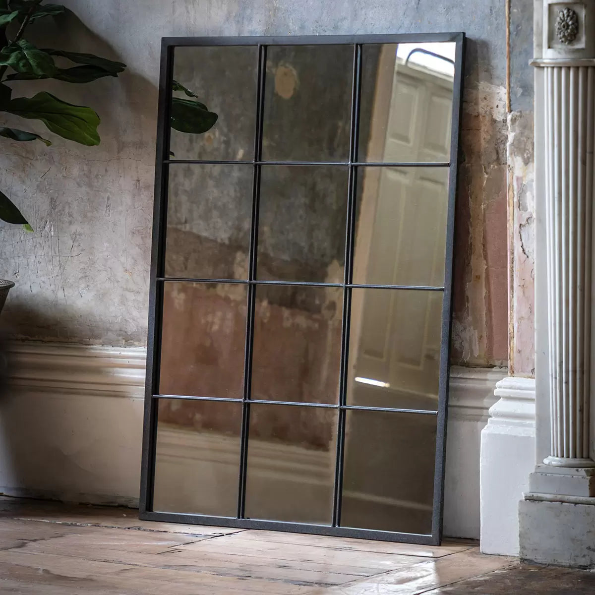 Front view of the Gallery Chafford matte black iron window pane mirror measuring 80x110cm mounted vertically on a bright neutral wall above a wooden console table.