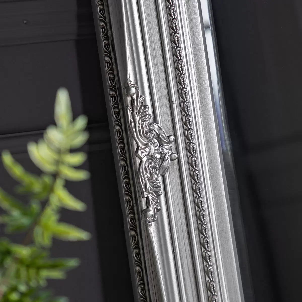 Full-length Gallery Hampshire antique silver leaner mirror with baroque wooden carved frame propped against a neutral living room wall.