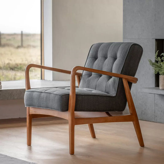 Front angle view of the Gallery Humber dark grey linen upholstered armchair with a natural solid oak angled frame in a brightly lit modern living room.