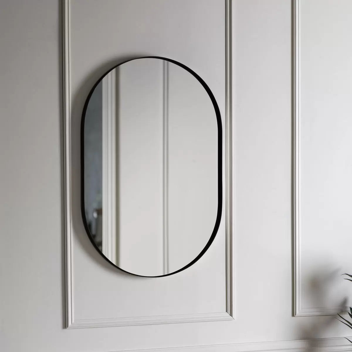 Front view of the Gallery Hurston Elipse Black Mirror showing its smooth curved iron frame and 60x90cm oval silhouette mounted on a minimalist wall.