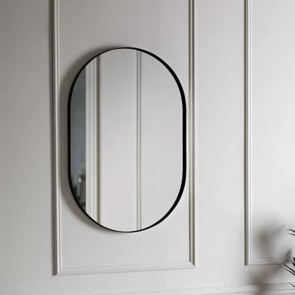 Front view of the Gallery Hurston Elipse Black Mirror showing its smooth curved iron frame and 60x90cm oval silhouette mounted on a minimalist wall.