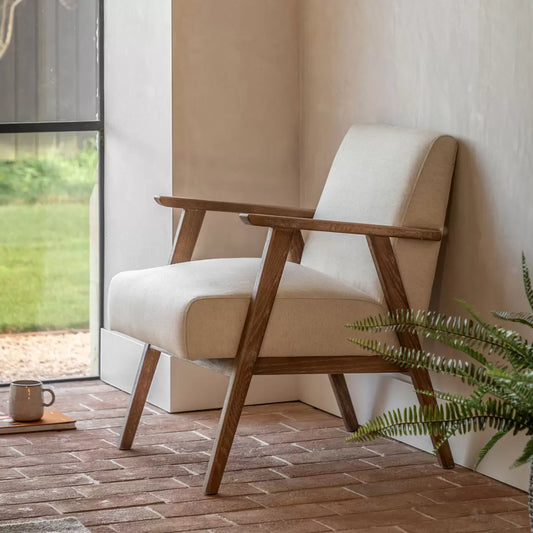 Front angle view of the Gallery Neyland Natural Linen Armchair featuring light cream linen fabric upholstery and a exposed light oak solid wood frame in a bright living room setup.