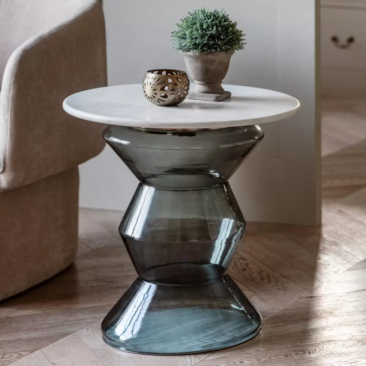 Gallery Turin Blue Side Table featuring a smooth deep-blue satin finish placed next to a modern armchair in a sunlit living room setting.