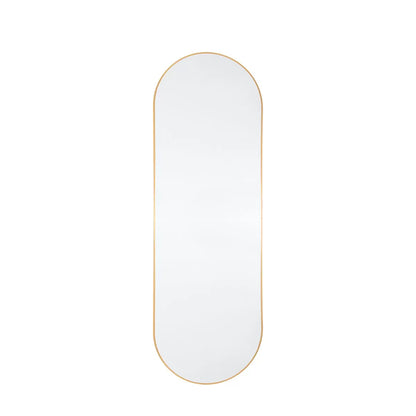 Full-length Gallery Yardley Gold Leaner Mirror with a rounded gold iron frame standing vertically in a bright modern living space reflecting natural sunlight.