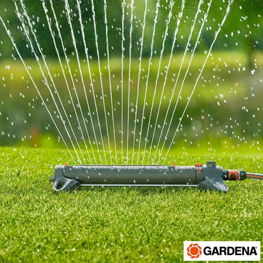 A Gardena AquaZoom Large Oscillating Sprinkler positioned on a green lawn, spraying a wide arc of water.