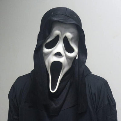 Front view of an adult wearing a classic white Ghost Face horror mask with an integrated black cloth hood in a dark setting