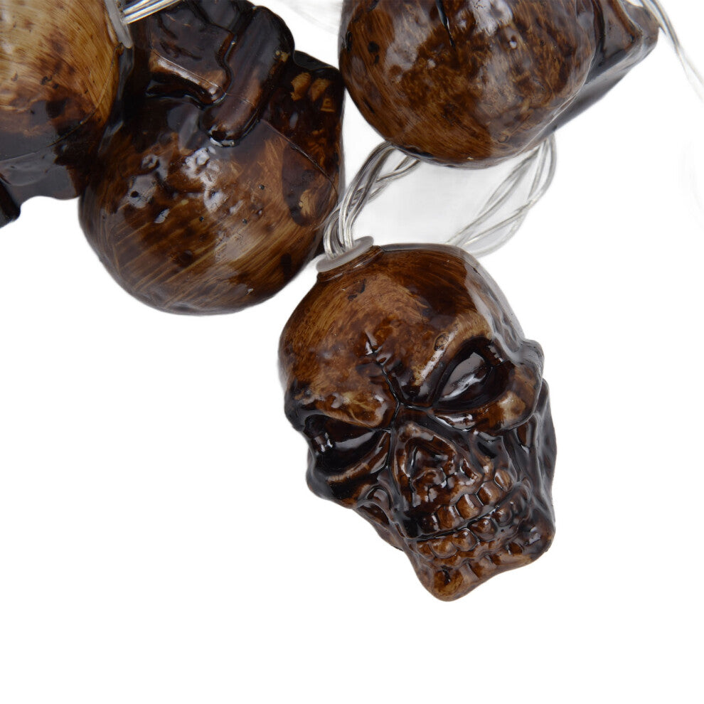 A string of 10 ghost skull lantern LED lights glowing warmly on a dark outdoor patio tree decorated for Halloween.