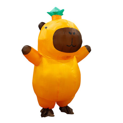 A person wearing a giant, light brown inflatable capybara costume with a smooth waterproof texture, standing outdoors on green grass ready for a party.