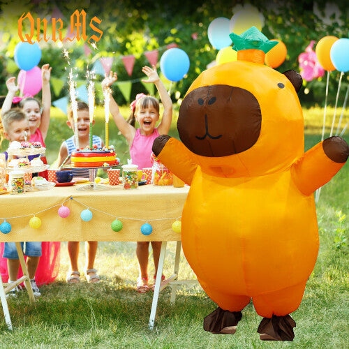 A person wearing a giant, light brown inflatable capybara costume with a smooth waterproof texture, standing outdoors on green grass ready for a party.