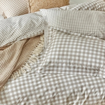 Flat-lay view of the single natural cotton gingham duvet cover set showcasing the reversible beige-and-white check pattern and structured Oxford border pillowcase on a rustic wood background.