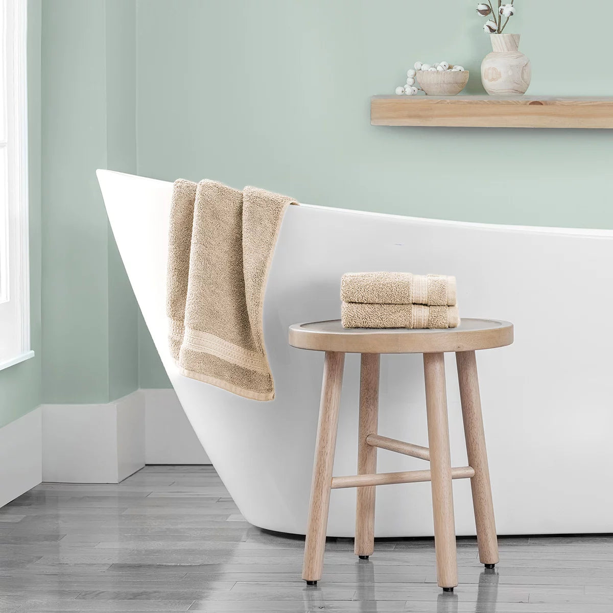 Stack of three plush 670 GSM Grandeur 100% cotton hand towels in three stylish colors neatly folded on a modern bathroom shelf.