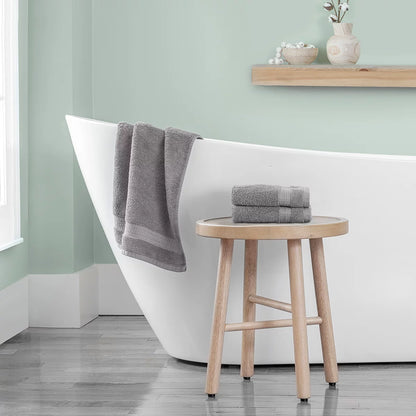 Stack of three plush 670 GSM Grandeur 100% cotton hand towels in three stylish colors neatly folded on a modern bathroom shelf.