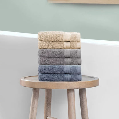 Stack of three plush 670 GSM Grandeur 100% cotton hand towels in three stylish colors neatly folded on a modern bathroom shelf.