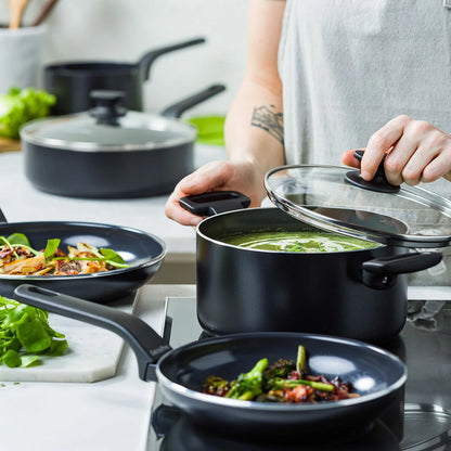A complete 9-piece GreenPan Essence cookware set in a sleek black finish, arranged neatly on a modern marble kitchen countertop.