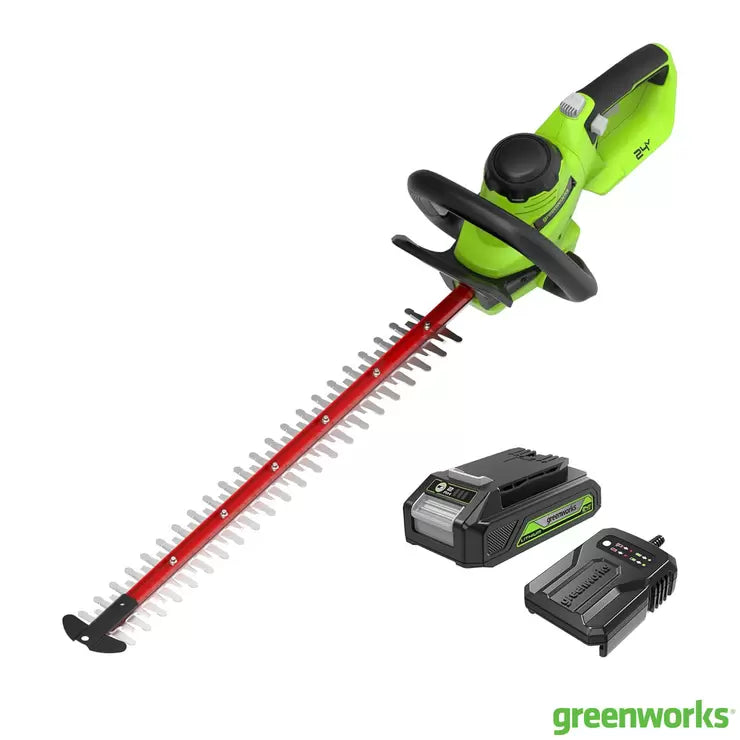 Greenworks 24V cordless brushless hedge trimmer with a long 61cm blade and a 2Ah battery being used on a garden hedge.
