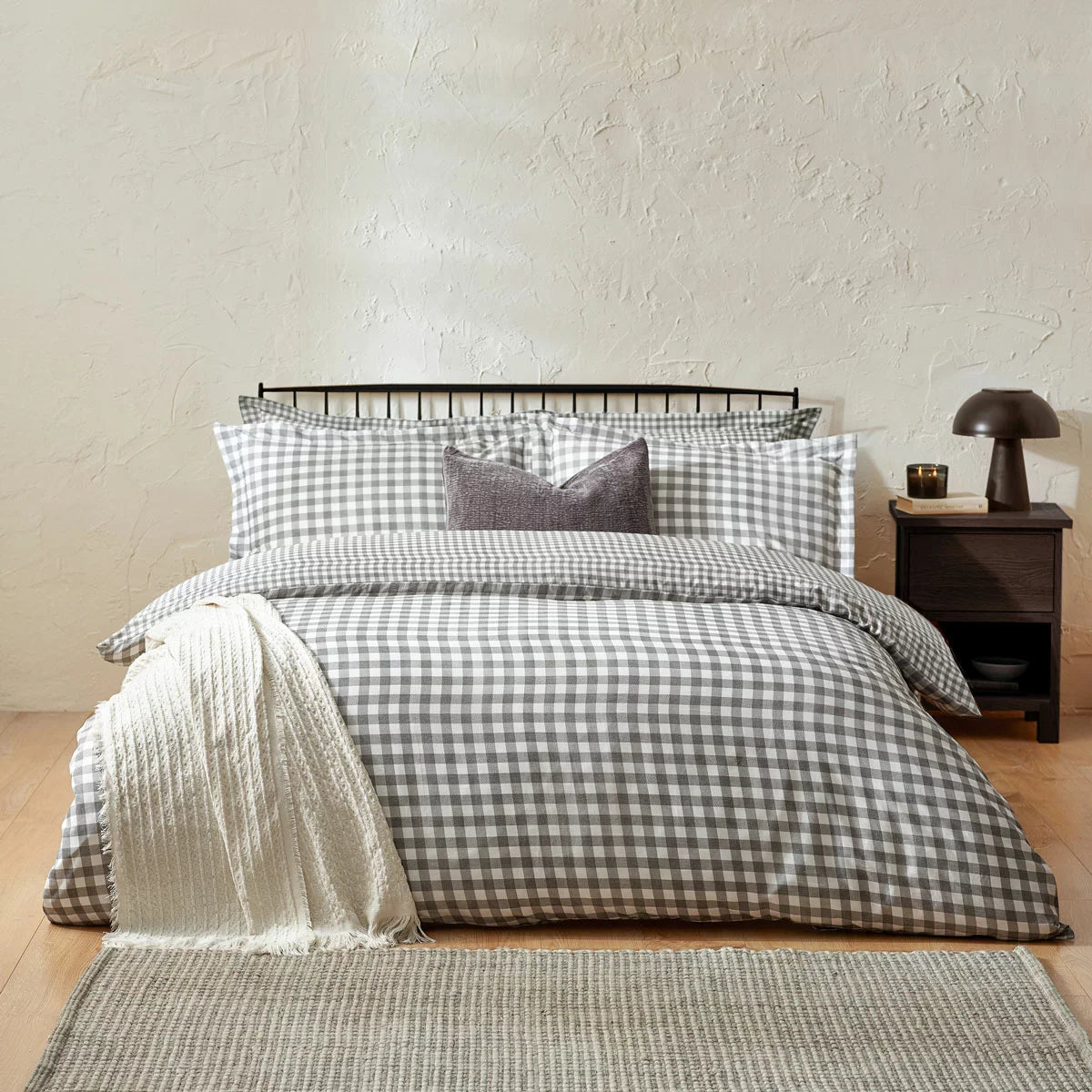 Overhead product shot of the grey and white gingham single duvet cover set neatly laid out on a gray bedframe with its matching Oxford border pillowcase highlighting the textured fabric finish.