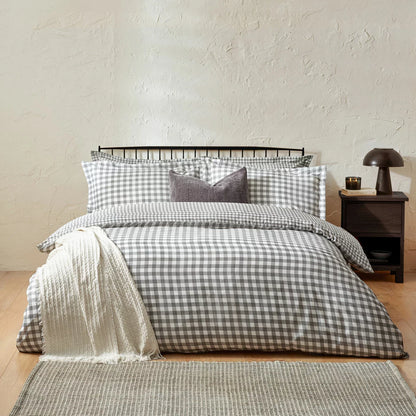 Overhead product shot of the grey and white gingham single duvet cover set neatly laid out on a gray bedframe with its matching Oxford border pillowcase highlighting the textured fabric finish.