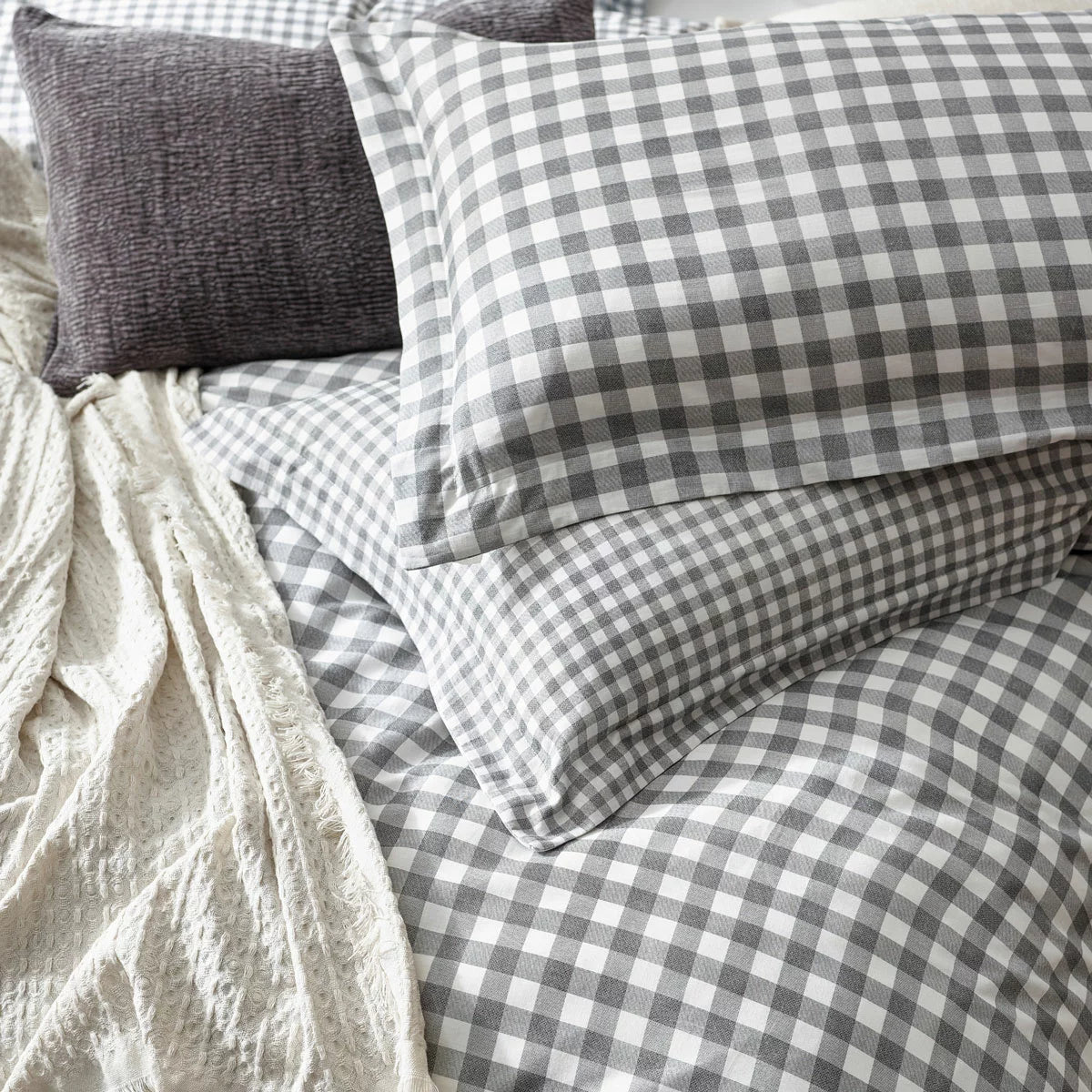 Overhead product shot of the grey and white gingham single duvet cover set neatly laid out on a gray bedframe with its matching Oxford border pillowcase highlighting the textured fabric finish.