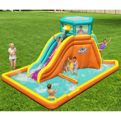 H2OGO! Tidal Tower orange inflatable mega water park with climbing tower, water slide, splash pool, crawl-through tunnel, sprinkler wall, and dump bucket set up in a sunny family garden