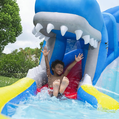 H2OGO! Whales 'n Waves blue inflatable kids water park with whale-themed slide, climbing wall, splash pool, built-in water sprayers, and interactive water blasters set up in a sunny garden-3